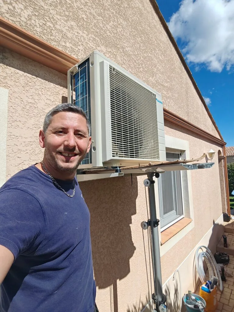 Artisan devant une unité extérieure de climatisation en cours de pose sur console murale, lève-matériaux déployé
