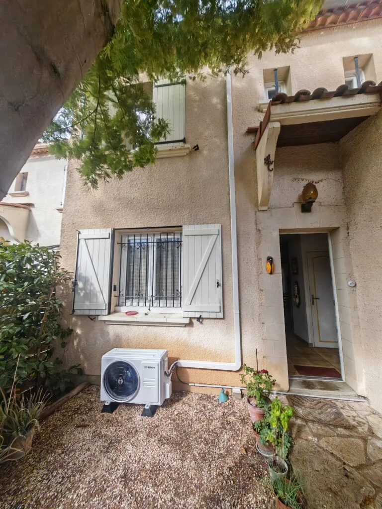 Unité extérieure Bosch posée au sol devant une maison, liaisons remontées dans une goulotte